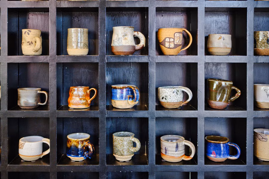 Handmade ceramic mugs on a dark shelf